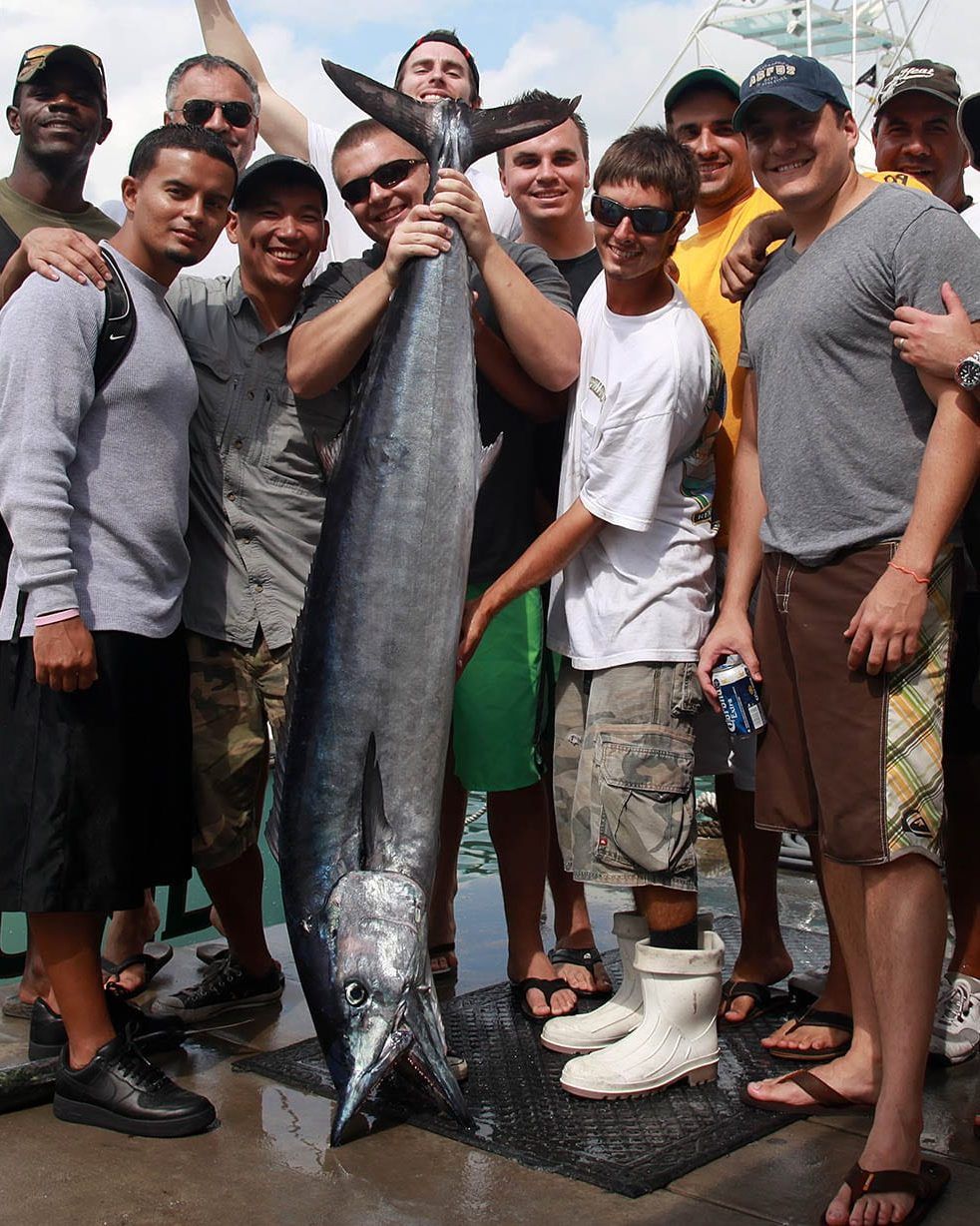 Bachelor party group posing with a big wahoo dockside next to Spellbound