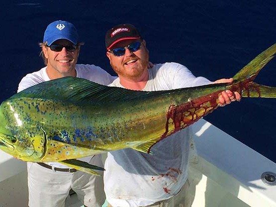 Two anglers holding a bull mahi aboard Spellbound off Miami