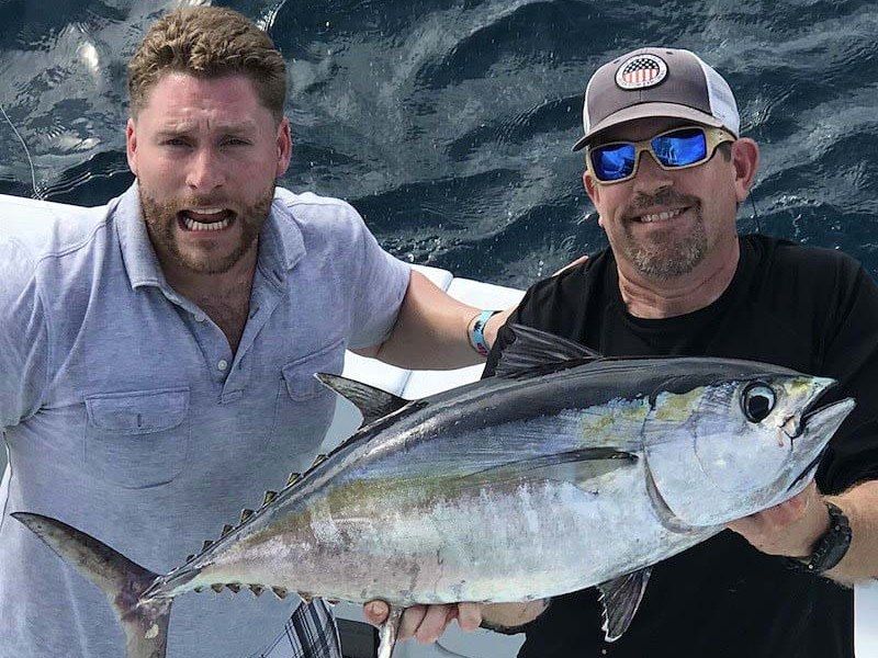 Two anglers holding a blackfin tuna caught offshore aboard Spellbound, Miami