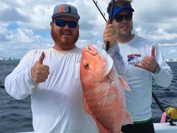 Two anglers with a red snapper caught on the reefs aboard Spellbound, Miami